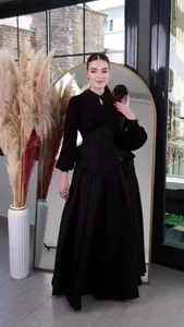 Full length view of an elegant black long-sleeved maxi dress with a cinched waist in a mirror