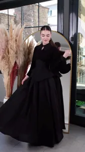 Elegant long-sleeved black maxi dress featuring a cinched waist and flowing pleated skirt