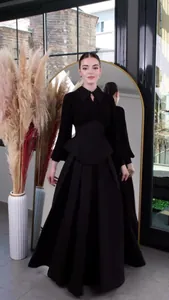 Elegant long-sleeved black maxi dress featuring a peplum waist and pleated skirt detail.