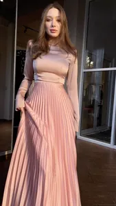 Elegante roze maxi-jurk met lange mouwen van geplooid satijn met een glanzende afwerking en pasvorm