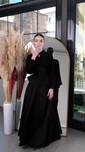 Full-length view of an elegant black long-sleeved maxi dress in a modern studio setting