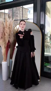 Elegant black long-sleeved floor-length dress with cinched waist and beaded collar detail