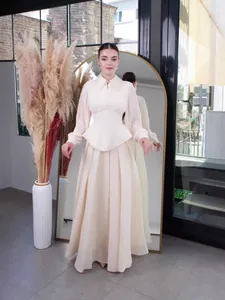 Elegant cream long sleeve maxi dress with a structured cinched waist and pleated skirt