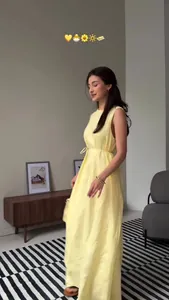Elegant sleeveless yellow maxi dress shown on a model in a cozy indoor setting