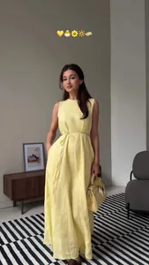 Sleeveless pale yellow maxi dress with waist tie and pockets in lifestyle setting