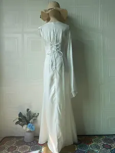 Detail view of white silky long-sleeve dress featuring back corset lacing design