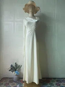 Elegant ivory satin long sleeve evening gown with pleated bodice on a mannequin