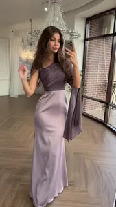 Close-up of elegant purple satin dress with one-shoulder pleated design and flowing sleeve.