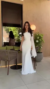 Elegant white one-shoulder floor-length dress with flowing long cape sleeve detail