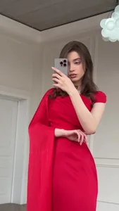 Detail of an elegant red silky slim-fit maxi dress with a unique draped sleeve.