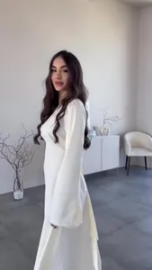 Elegantes langärmliges weißes Maxikleid mit fließender Silhouette in minimalistischem Raum
