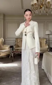 Elegant wit blazerpak met lange mouwen en maxi-jurk van gebloemd kant in luxe kamer