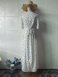 Rückansicht eines weißen Vintage-Maxikleides mit schwarzen Punkten und Taillenband