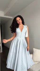 Elegant light blue V-neck sleeveless maxi dress with pleated skirt on model.