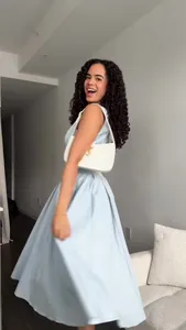 Woman wearing a light blue V-neck sleeveless maxi dress in a bright indoor setting
