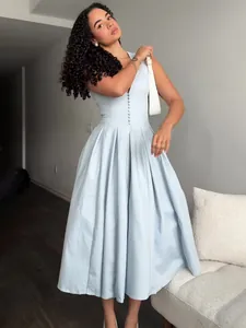 Elegant light blue V-neck sleeveless midi dress with pleated skirt shown on a model