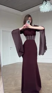 Detail eines eleganten weinroten Langarmkleides mit weiten Ärmeln und Korsett-Taille