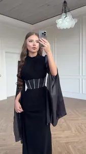 Detailansicht eines eleganten schwarzen Langarmkleids mit Cape-Ärmeln und Wespentaille