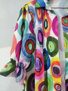 Close-up of vibrant colorful circle print dress with smocked cuff detail.