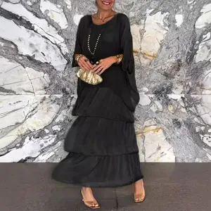 Elegant black tiered maxi dress with loose fit and stylish gold clutch accessory