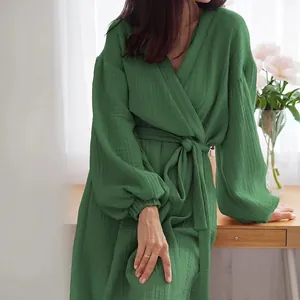 Close-up detail of green long-sleeved wrap dress featuring elegant pleated gauze fabric