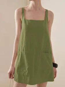 Dettaglio di un mini abito verde senza maniche con grandi tasche funzionali