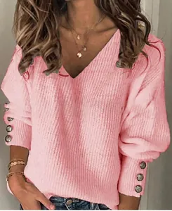 Dettaglio di un top in maglia rosa con scollo a V e bottoni decorativi sui polsini.