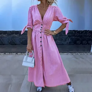 Detailweergave van de roze jurk met V-hals, knopen en stijlvolle gestrikte mouwen