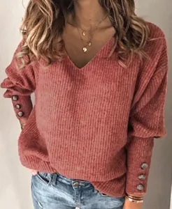Dettaglio di un maglione rosa in maglia a maniche lunghe con scollo a V e bottoni per donne.
