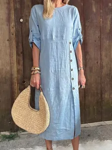 Detalle de vestido midi de lino azul con botones laterales y bolso de paja