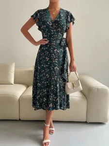 Close-up of a dark green floral wrap dress with butterfly sleeves and a ruffled hem.