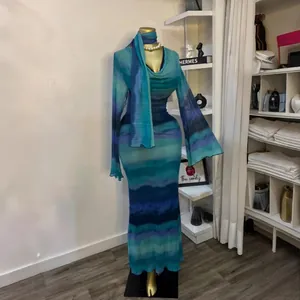 Vista dettagliata dell'abito lungo tie-dye blu e verde con una sciarpa coordinata.