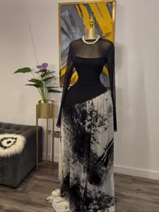 Robe longue élégante en résille noire à manches longues avec jupe à imprimé abstrait.