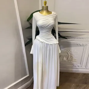 Detalle de un elegante vestido largo blanco plisado de manga larga con ribete de volantes