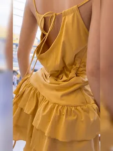 Vista posteriore di un mini abito giallo senza maniche con volant e fiocco sulla schiena
