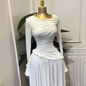 Detalle de vestido largo blanco de manga larga con cuerpo plisado y volantes elegantes