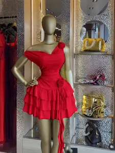 Dettaglio dell'abito corto rosso monospalla con balze e fiori 3D su manichino dorato