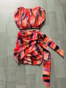 Vibrant abstract tie-dye print two-piece set featuring sleeveless top and draped skirt.