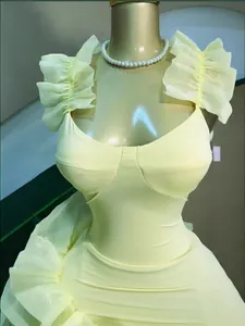 Close-up detail of light yellow ruffled strap dress with flattering cinch waist design.
