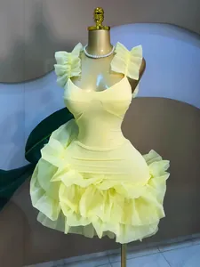 Close-up of a light yellow sweet style dress with ruffled straps and bubble skirt detail.