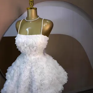 Detailopname van een witte mouwloze jurk met 3D-rozenbloemen op een etalagepop