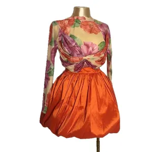 Elegante set 2 pezzi con top floreale in mesh e minigonna a palloncino arancione.