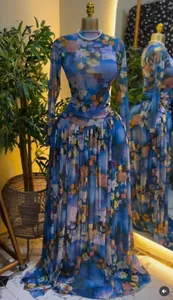 Gedetailleerd zicht op de bloemenprint van een elegante geplooide maxi-jurk met lange mouwen.
