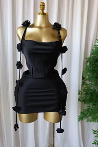 Close-up detail of black sleeveless mini dress with 3D floral accents and corset waist