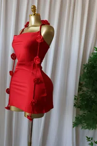 Close-up detail of a red sleeveless mini dress featuring 3D rose flower pins on a gold mannequin