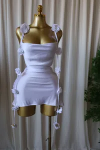 Elegant white sleeveless mini dress with 3D flower decorations on a gold mannequin