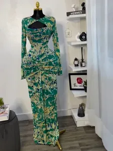 Full view of a green and yellow printed long-sleeve maxi dress with chest cut-out detail