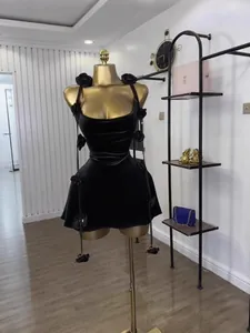 Elegant black sleeveless mini dress featuring 3D floral accents on a golden mannequin