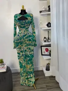 Detail view of green printed long-sleeved maxi dress with ruched waist and cut-out.