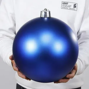Detailansicht einer großen mattblauen Weihnachtskugel, die von Hand gehalten wird